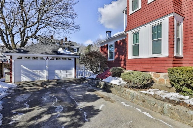 view of property exterior featuring a shingled roof and a detached garage