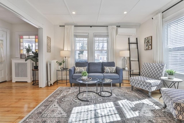 living area featuring recessed lighting, radiator heating unit, an AC wall unit, and wood finished floors