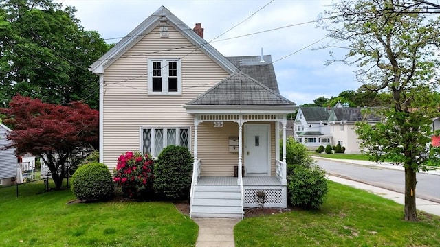 142 Dale St, Waltham, MA 02451 - view of front of house featuring a front yard, a chimney, and covered porch