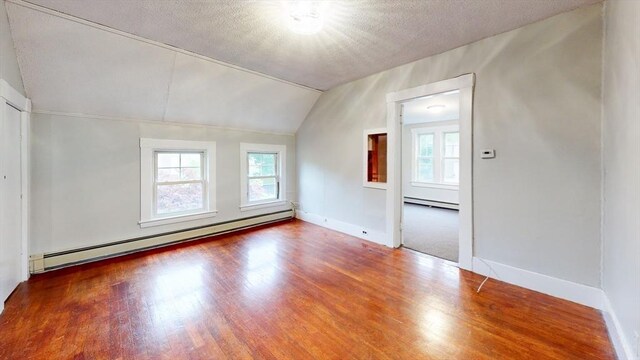 142 Dale St, Waltham, MA 02451 - unfurnished room featuring baseboard heating, plenty of natural light, wood finished floors, lofted ceiling, and a textured ceiling