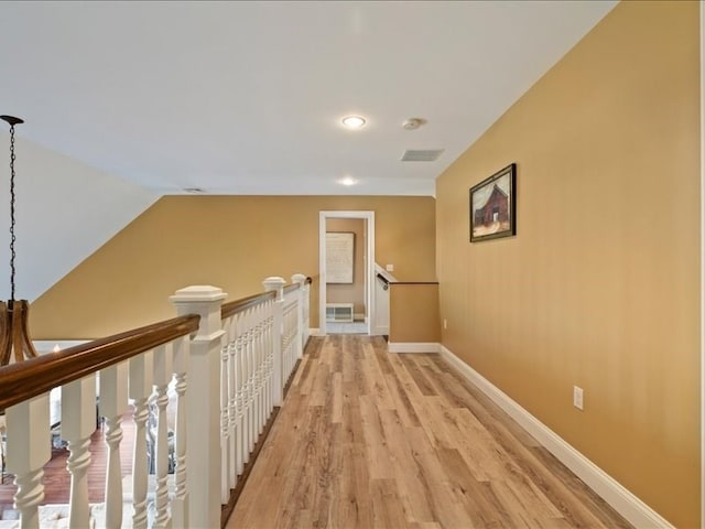 hallway with lofted ceiling and light hardwood / wood-style flooring