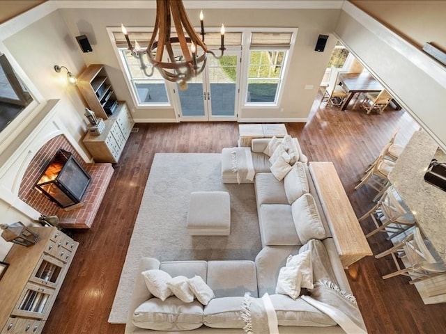 living room with dark hardwood / wood-style flooring, a brick fireplace, and an inviting chandelier