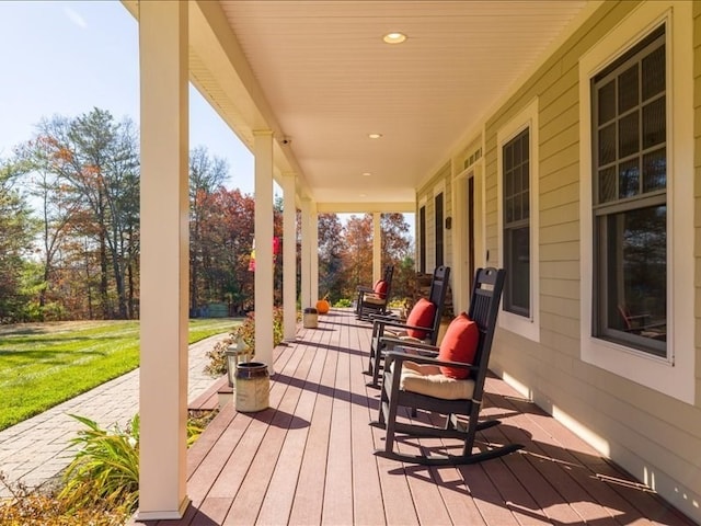 wooden deck featuring a porch and a yard