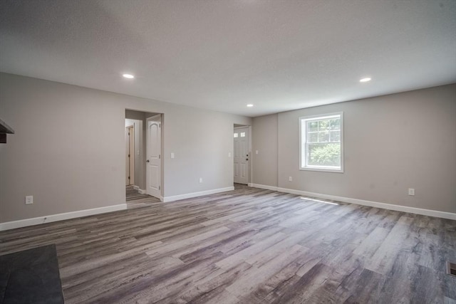 unfurnished room with baseboards, wood finished floors, and recessed lighting