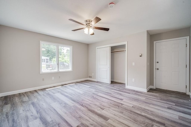 unfurnished bedroom featuring a ceiling fan, a closet, baseboards, and wood finished floors