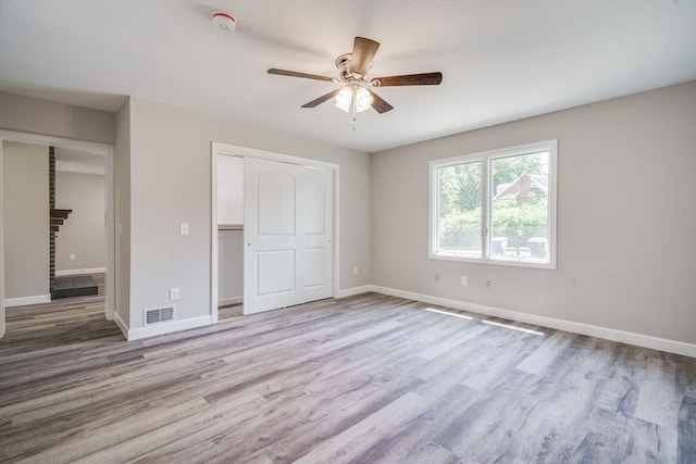 unfurnished bedroom featuring baseboards, visible vents, wood finished floors, a brick fireplace, and a closet