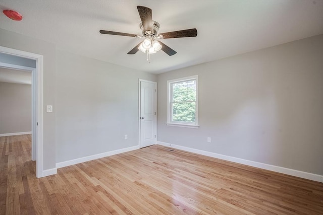 empty room featuring ceiling fan, light wood-style flooring, and baseboards