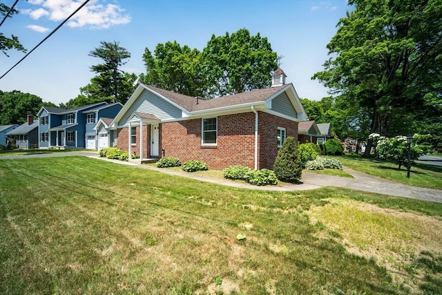 view of side of property with driveway, brick siding, a lawn, and an attached garage