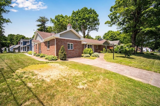 single story home with driveway, brick siding, and a front yard