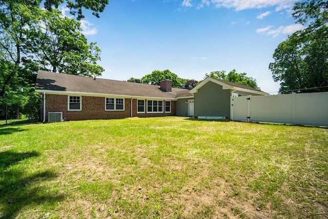 rear view of property with central AC, brick siding, a lawn, and a chimney