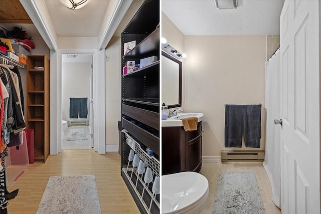 bathroom with vanity, toilet, hardwood / wood-style floors, and a baseboard heating unit