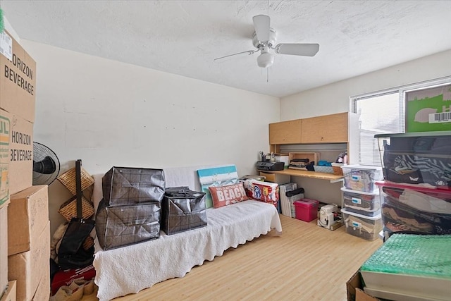 bedroom featuring ceiling fan, hardwood / wood-style floors, and a textured ceiling