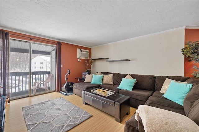 living room with crown molding, an AC wall unit, a textured ceiling, and light wood-type flooring