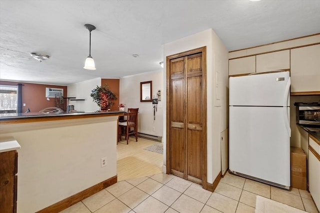 kitchen featuring a baseboard heating unit, a wall unit AC, white refrigerator, light tile patterned flooring, and decorative light fixtures