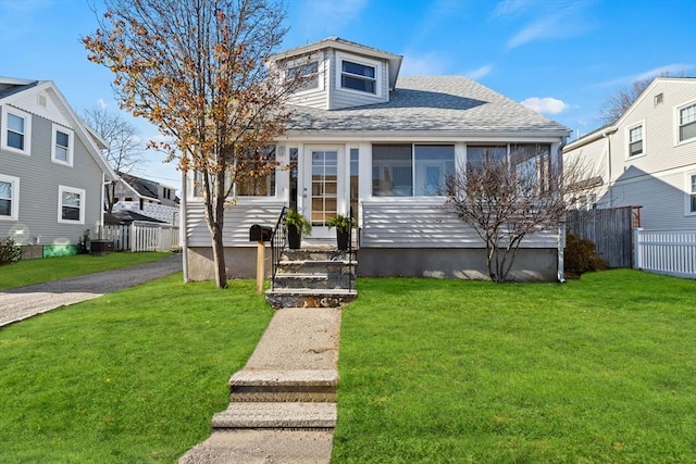 bungalow-style house featuring cooling unit, a front yard, and a sunroom