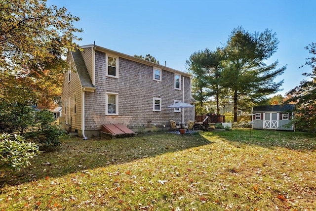 rear view of property featuring a yard, an outdoor structure, and a shed