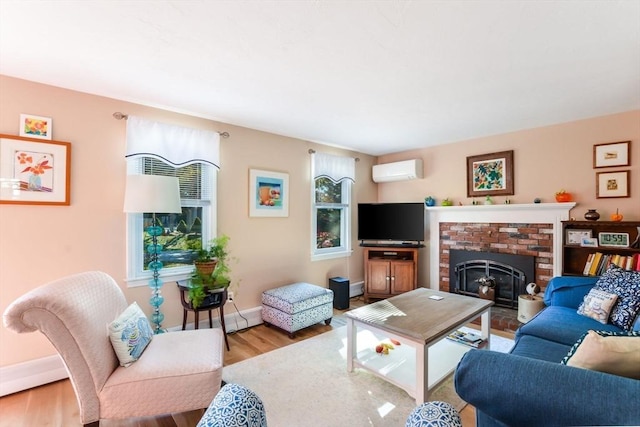 living room with a wall mounted air conditioner, baseboards, wood finished floors, and a fireplace