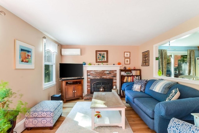 living area with a wall mounted air conditioner, a brick fireplace, and light wood-style flooring