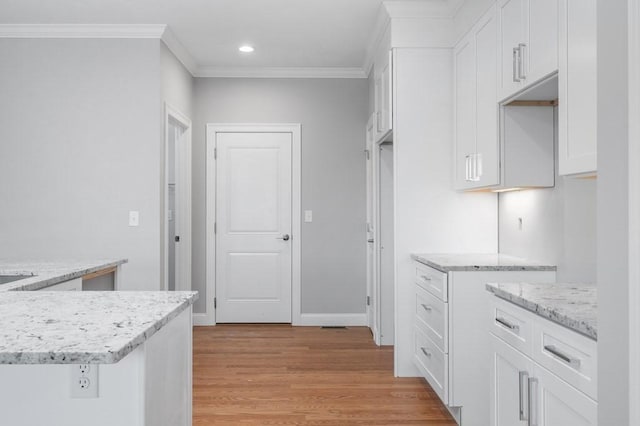 kitchen with white cabinets, light wood-style flooring, light stone countertops, crown molding, and recessed lighting