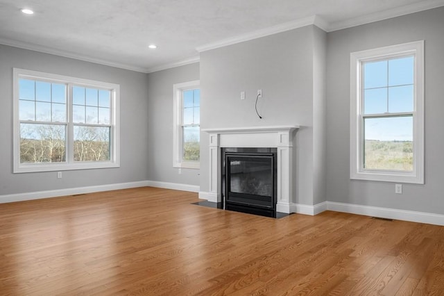 unfurnished living room with a fireplace with flush hearth, a wealth of natural light, baseboards, and wood finished floors