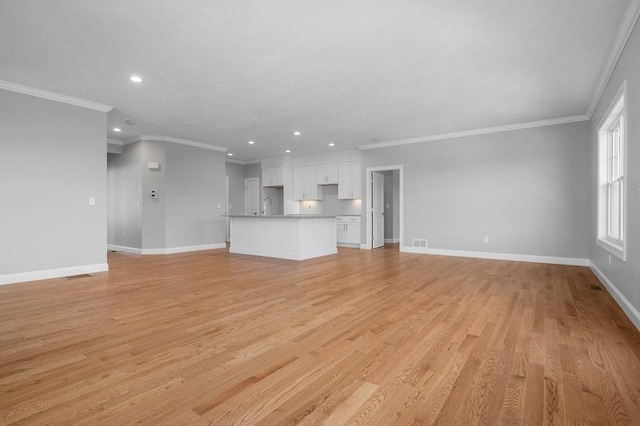 unfurnished living room featuring light wood-type flooring, crown molding, baseboards, and recessed lighting