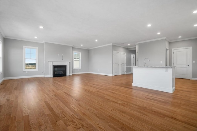 unfurnished living room featuring light wood-type flooring, a glass covered fireplace, and baseboards