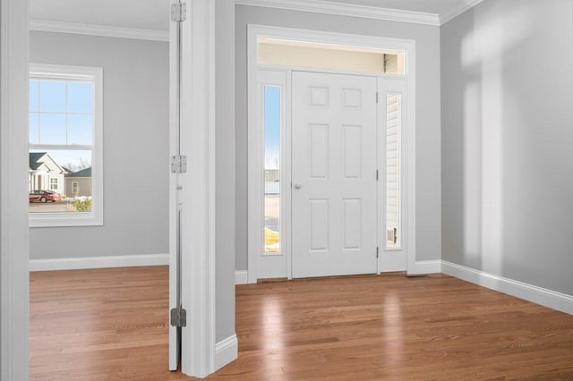 foyer featuring baseboards, ornamental molding, and wood finished floors