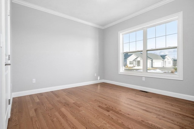 spare room with baseboards, wood finished floors, and crown molding