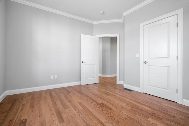 unfurnished bedroom featuring light wood-type flooring, baseboards, and ornamental molding