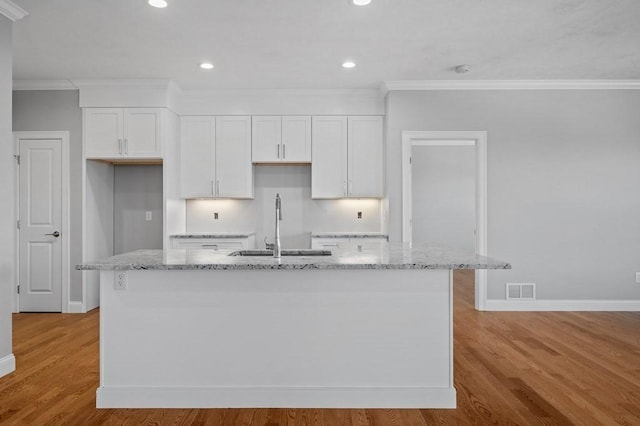 kitchen featuring light wood-style flooring, a kitchen island with sink, white cabinetry, and a sink