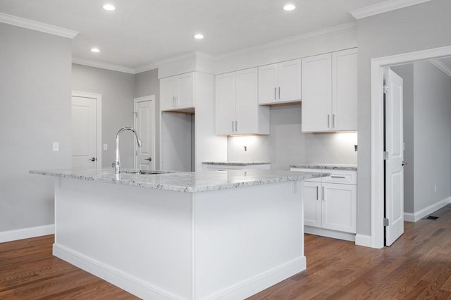 kitchen featuring ornamental molding, white cabinets, an island with sink, and wood finished floors