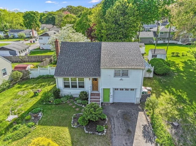 view of front facade with an attached garage, roof with shingles, driveway, a chimney, and a residential view