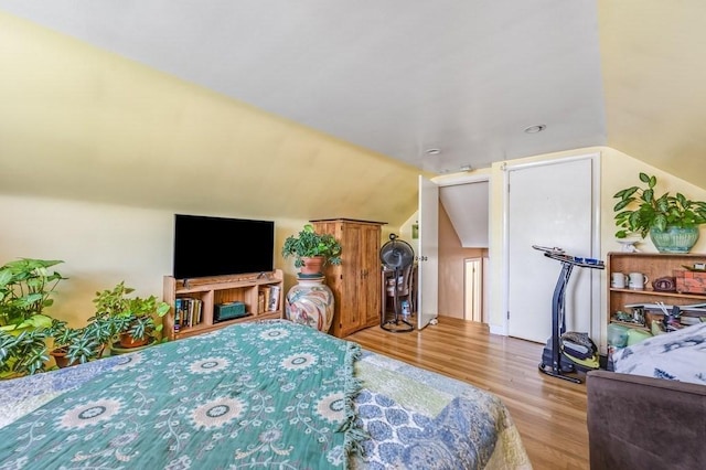 bedroom featuring wood finished floors and lofted ceiling