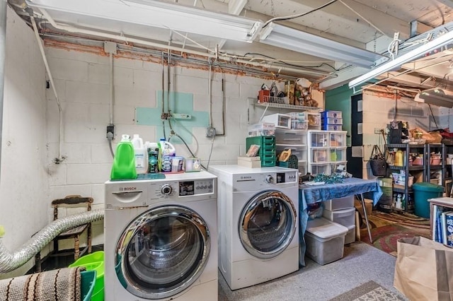 laundry area with independent washer and dryer and concrete block wall