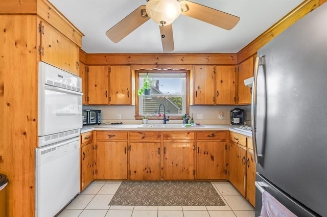 kitchen with freestanding refrigerator, dishwashing machine, white oven, a sink, and light countertops