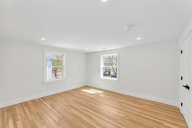 spare room featuring plenty of natural light, recessed lighting, baseboards, and light wood-type flooring