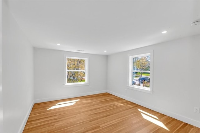 empty room with recessed lighting, baseboards, visible vents, and light wood finished floors
