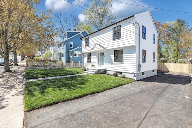 view of front of house with fence, a front yard, and aphalt driveway