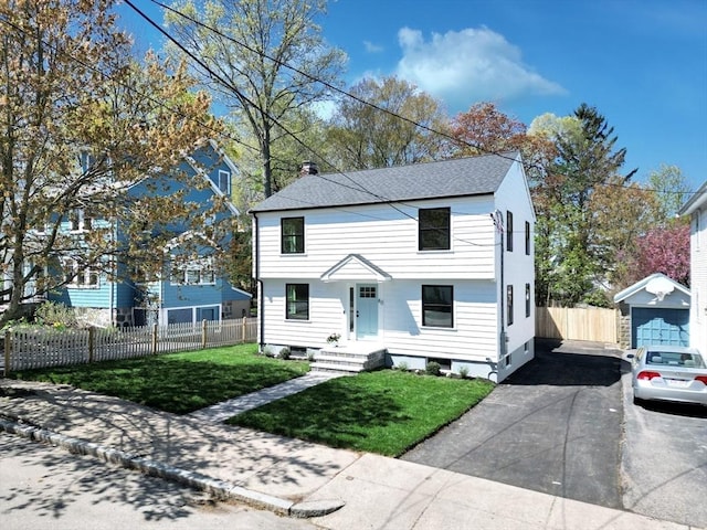 view of front of property featuring fence, a shingled roof, a front yard, an outbuilding, and concrete driveway