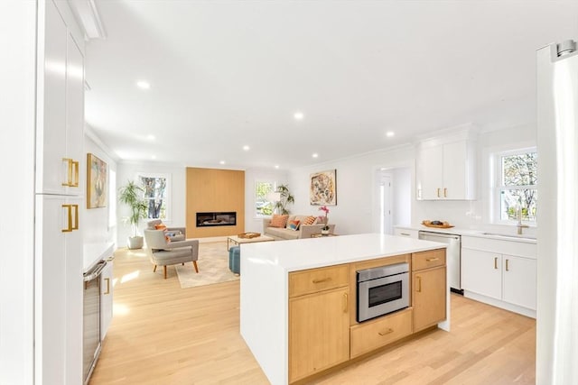 kitchen featuring a center island, ornamental molding, light wood finished floors, and stainless steel appliances