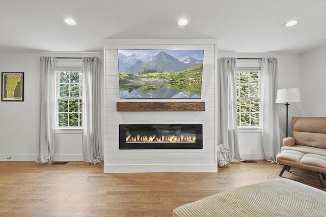 sitting room with recessed lighting, a healthy amount of sunlight, a fireplace, and wood finished floors