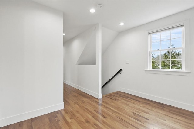 interior space featuring light wood-style flooring, baseboards, vaulted ceiling, and recessed lighting