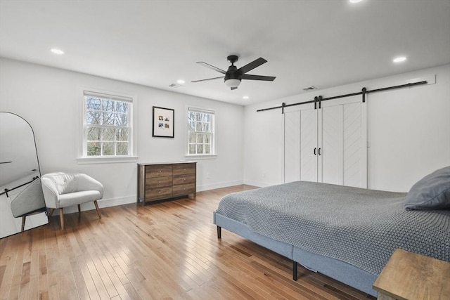 bedroom featuring ceiling fan, a barn door, recessed lighting, baseboards, and hardwood / wood-style floors