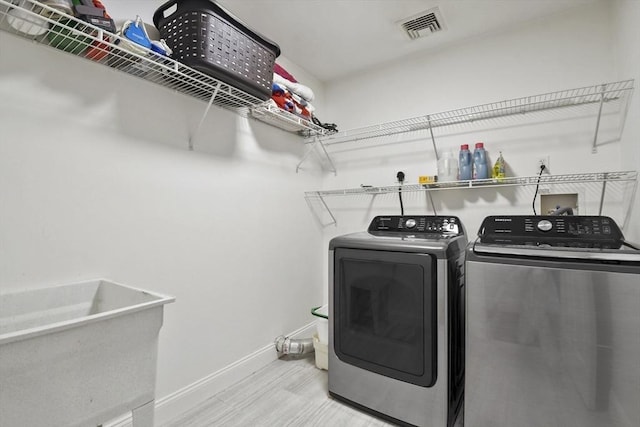 laundry area with laundry area, baseboards, visible vents, wood finished floors, and washing machine and clothes dryer