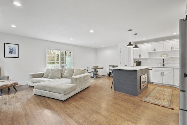 living area featuring light wood-style floors, baseboards, and recessed lighting