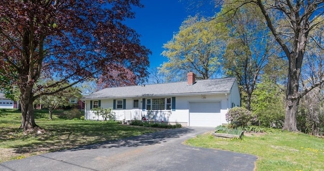 ranch-style home with driveway, a chimney, a front lawn, and a garage