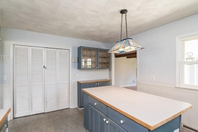 kitchen with glass insert cabinets, a wainscoted wall, a baseboard radiator, and light countertops