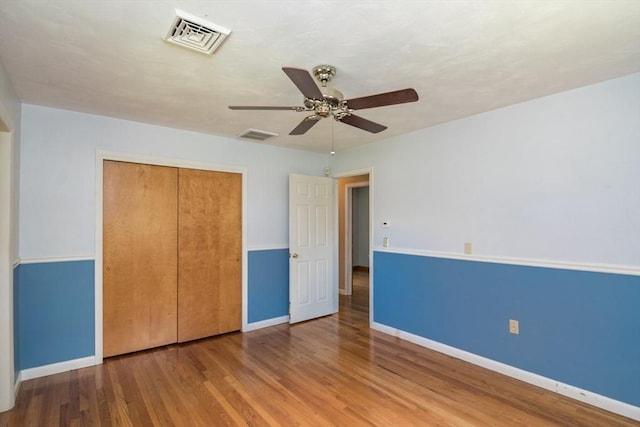 unfurnished bedroom featuring baseboards, visible vents, wood finished floors, and a closet