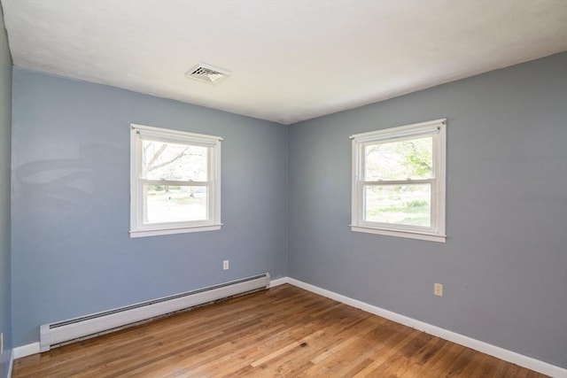 spare room featuring baseboards, a baseboard radiator, wood finished floors, and visible vents