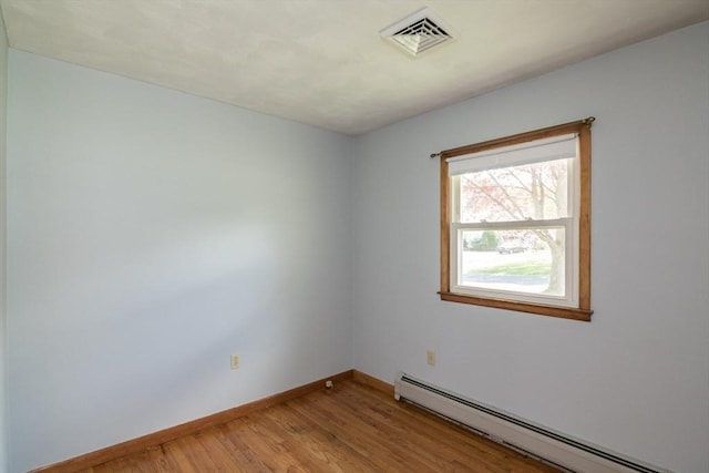 spare room featuring visible vents, baseboards, light wood-style flooring, and a baseboard heating unit
